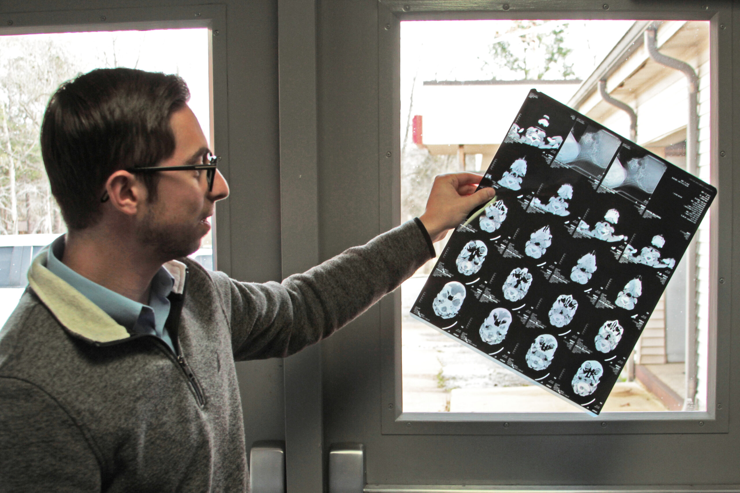 A photo shows Kyle Kopec holding a medical record up to the light by a window.