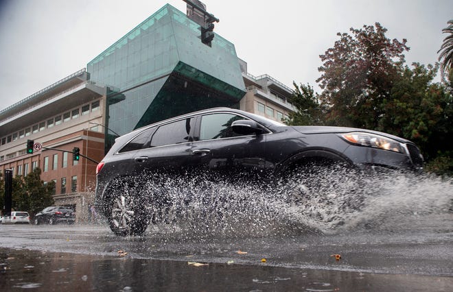 A car splashes through a puddle left by the first rain of the season on Weber Avenue near San Joaquin Street in downtown Stockton on Tuesday, Nov. 1, 2022.