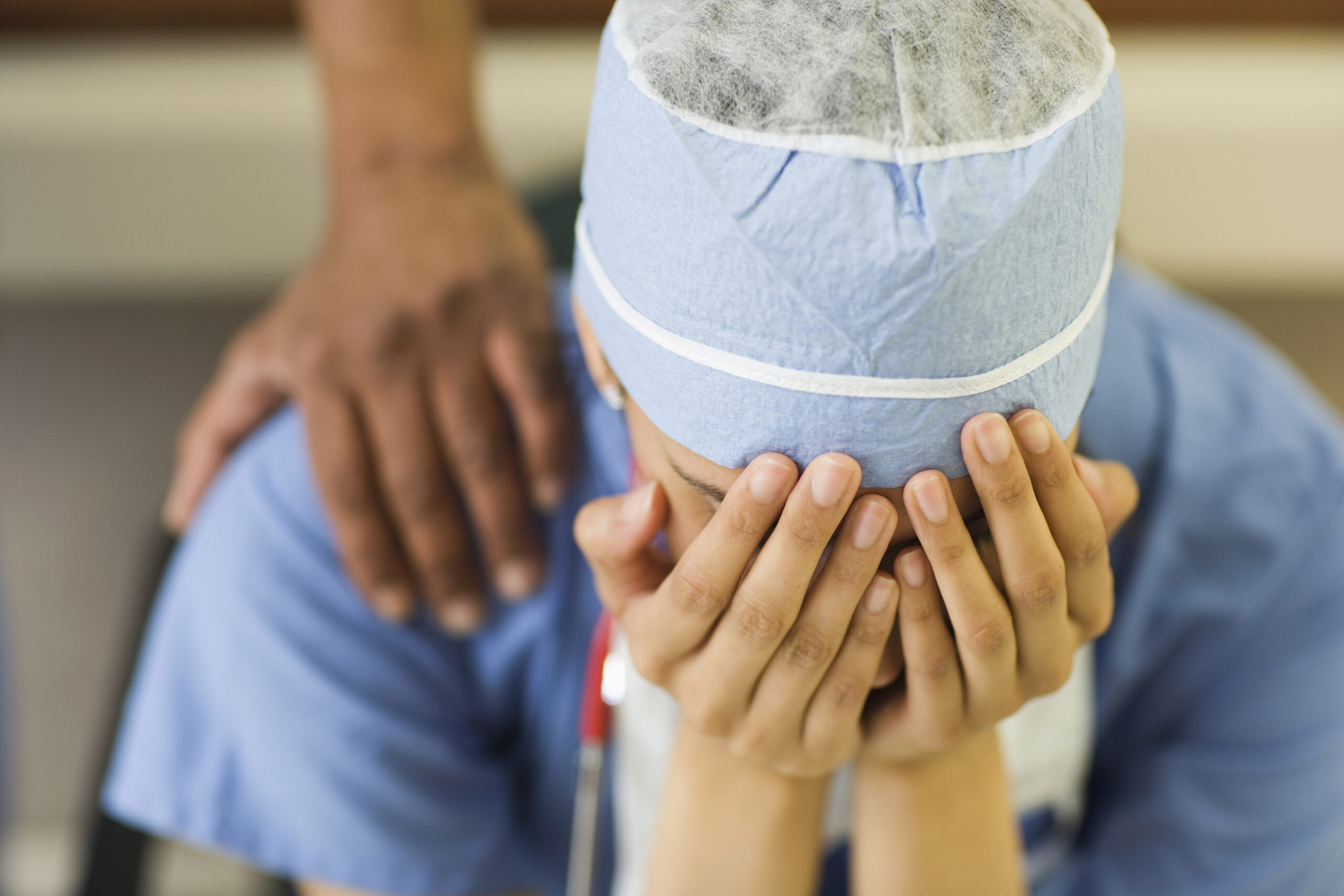A health care worker is. sitting with their head in their hands.