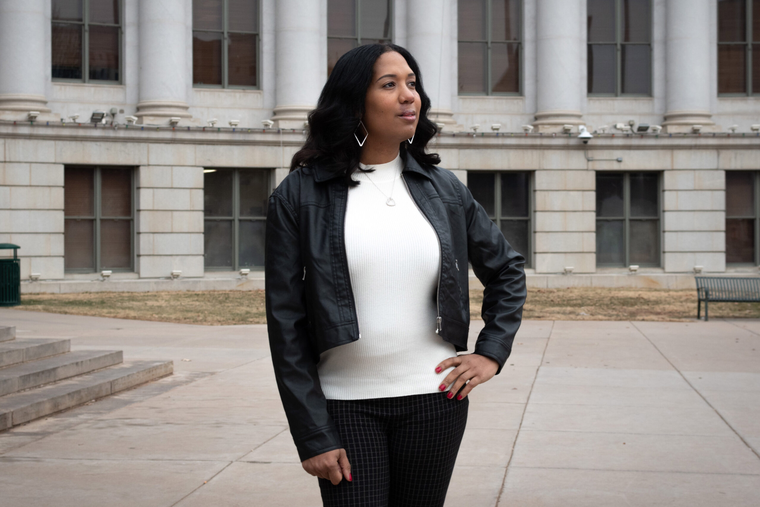 Taliyah Murphy stands outside the Denver City and County Building. She rests her left hand on her left hip and looks into the distance.